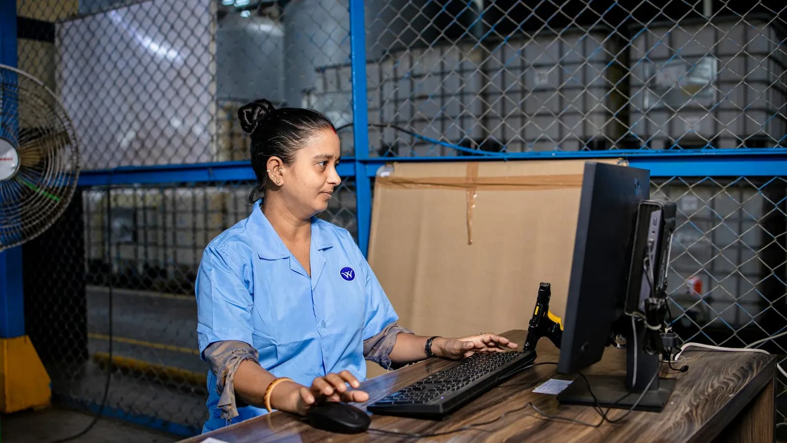 A stores coordinator placing an order at a computer inside a supplies warehouse