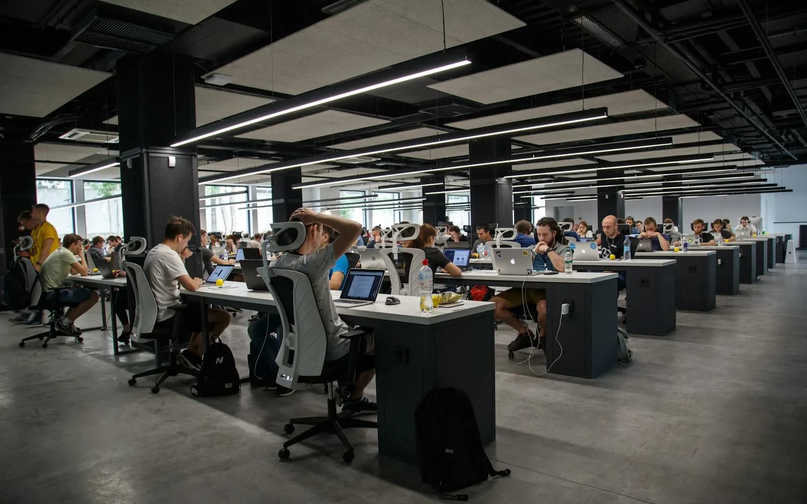 Open-plan technology office floor with long desk rows and staff at work