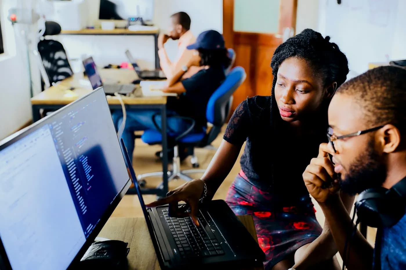 Two colleagues working together at a laptop in a shared office
