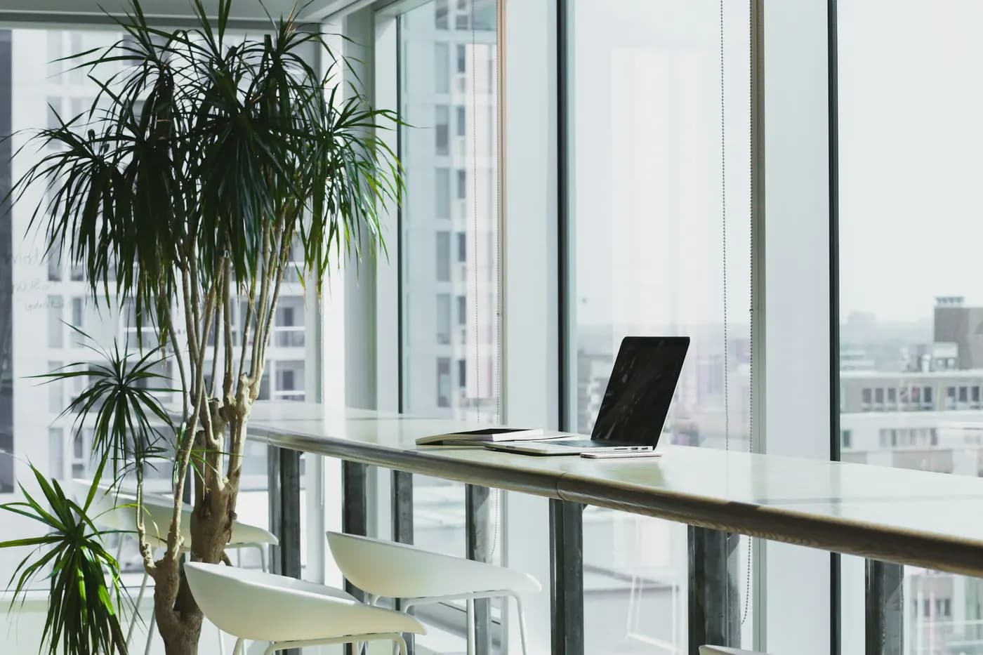 A prepared office workspace with a business laptop set out beside full-height windows