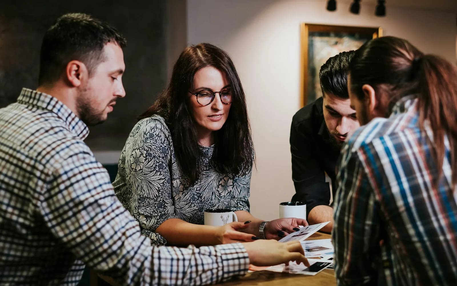 Four colleagues around a table reviewing printed pages together